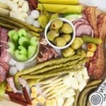 Overhead view of a completed board. The toppings are a variety of meats, cheeses, pickles, olives, pepper, vegetables.