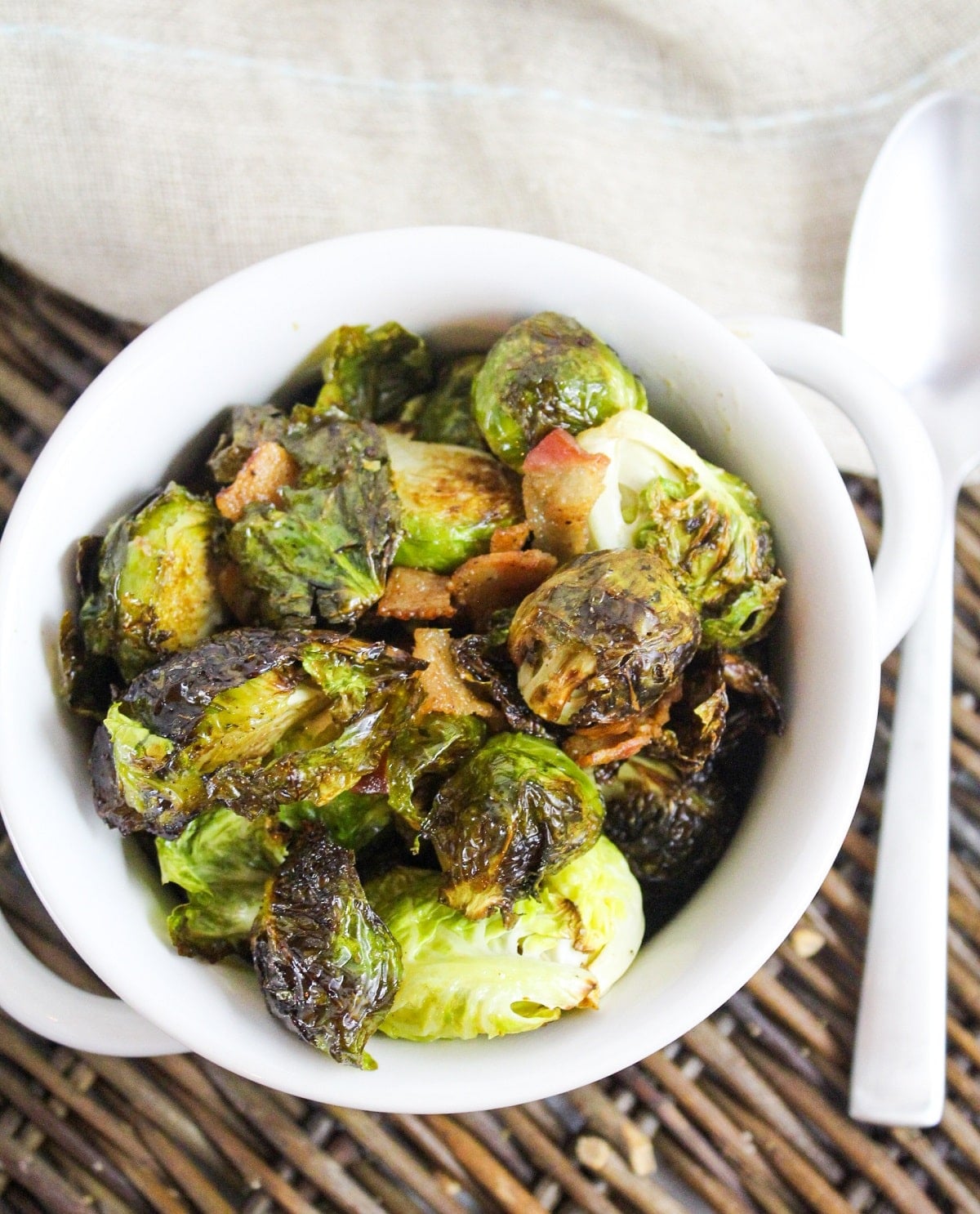 cooked brussels sprouts and bacon in a white bowl.