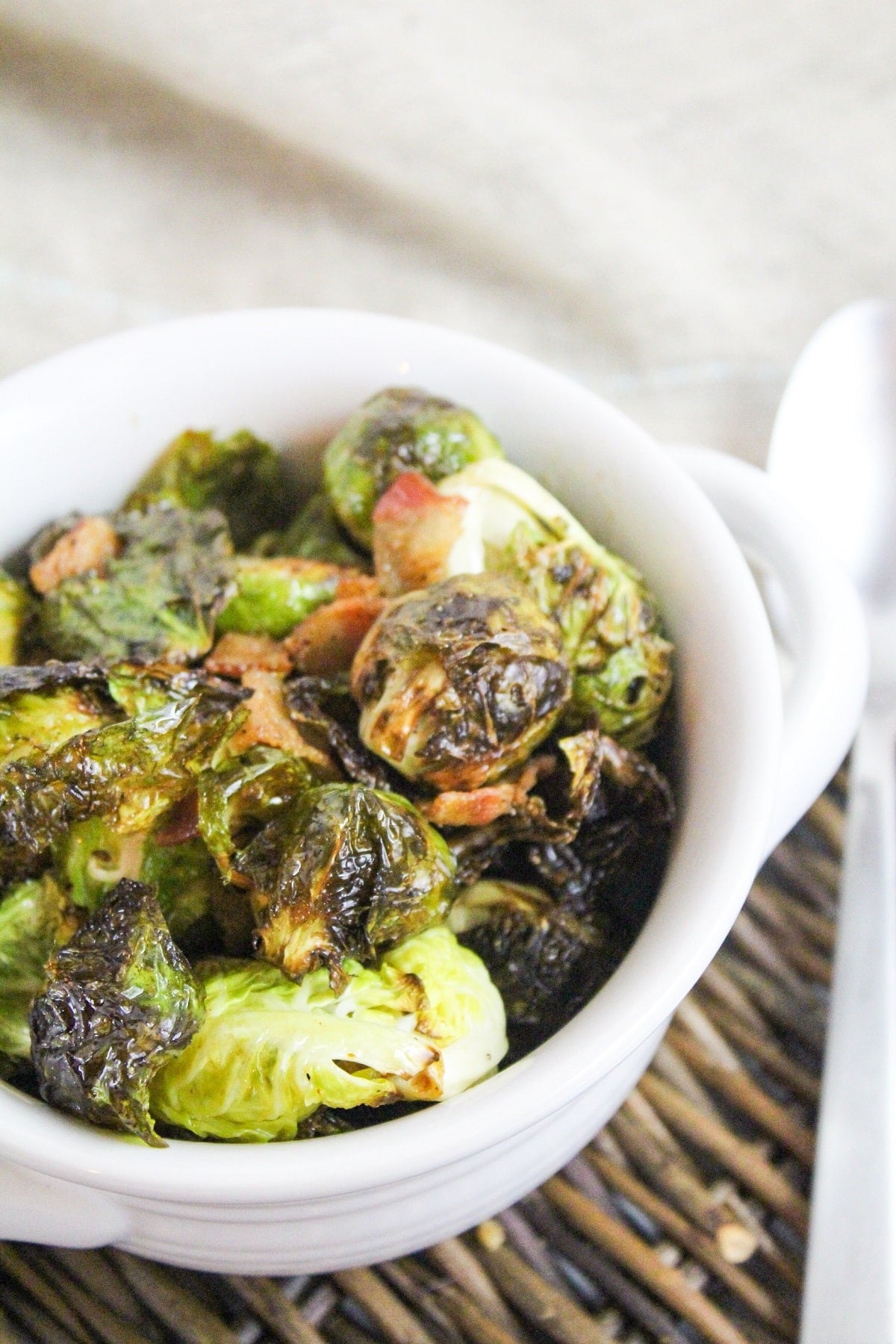 cooked brussels sprouts and bacon in a white bowl.