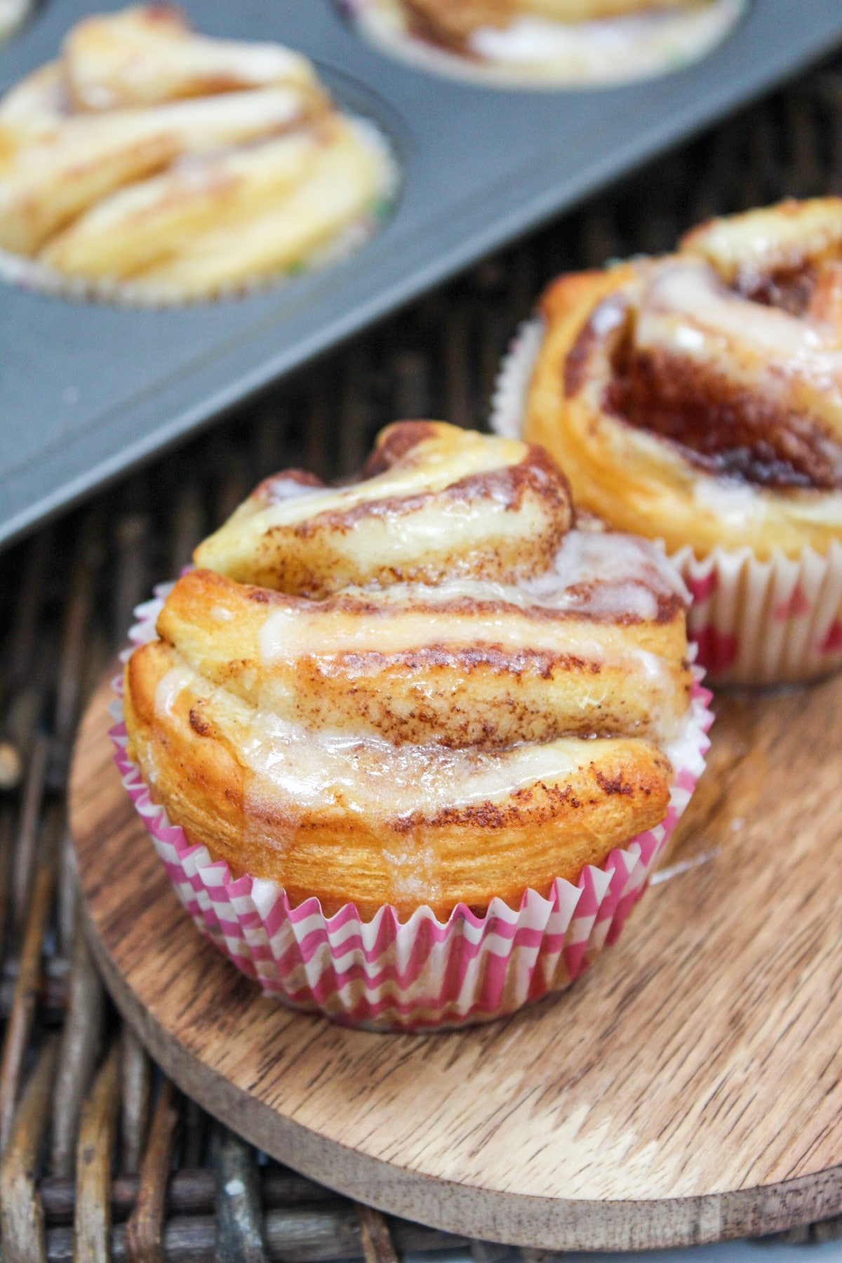 individual cinnamon rolls in a muffin tin with a glaze on top.