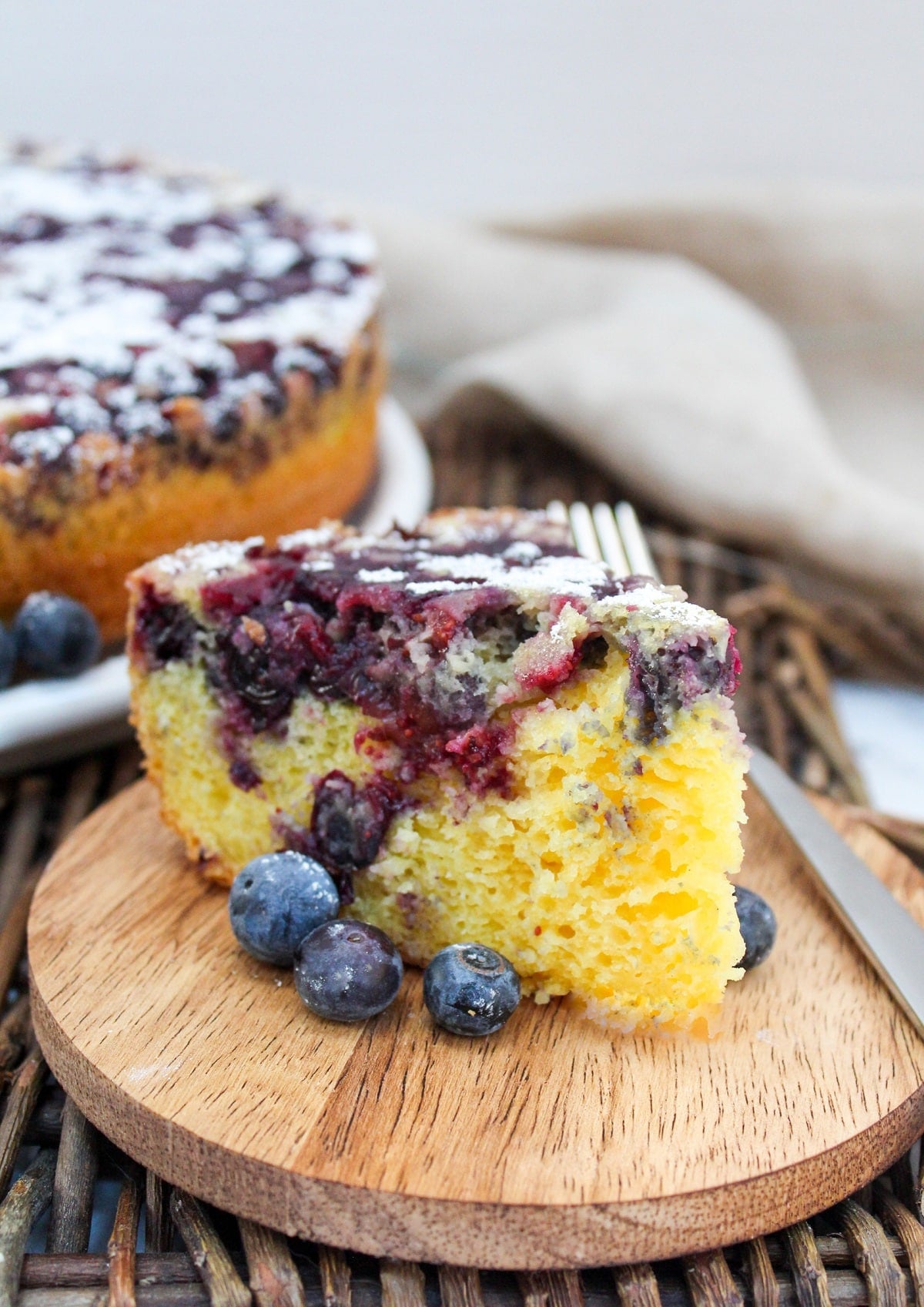 single slice of blueberry lemon cake with fresh blueberries on the side.