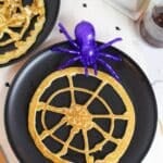 pancakes shaped like a round spider web with a plastic purple spider on the side.