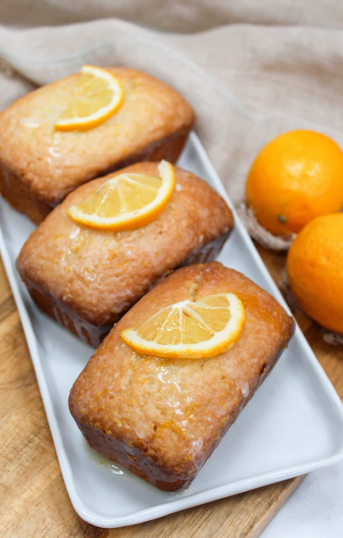 Mini pound cake loaves topped with a glaze and fresh lemon wedges.