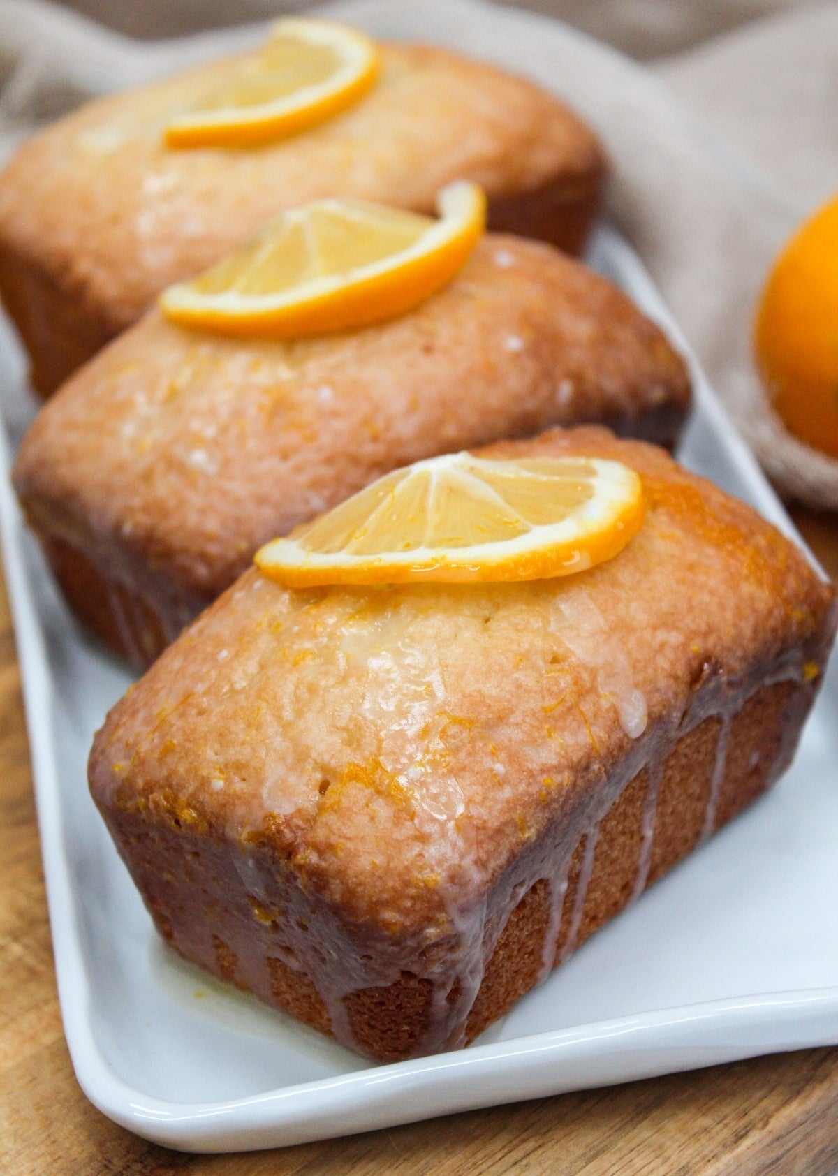Mini pound cake loaves topped with a glaze and fresh lemon wedges.