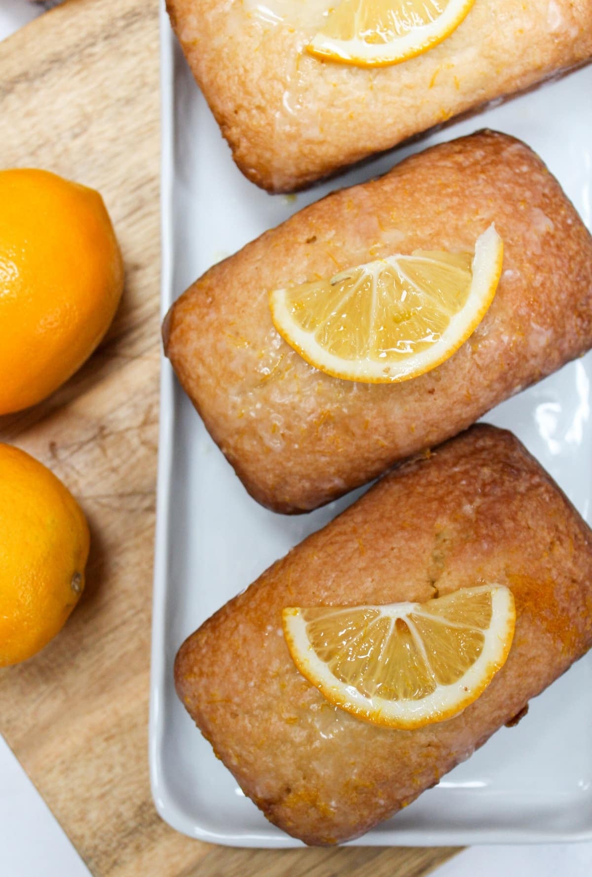 Mini pound cake loaves topped with a glaze and fresh lemon wedges.