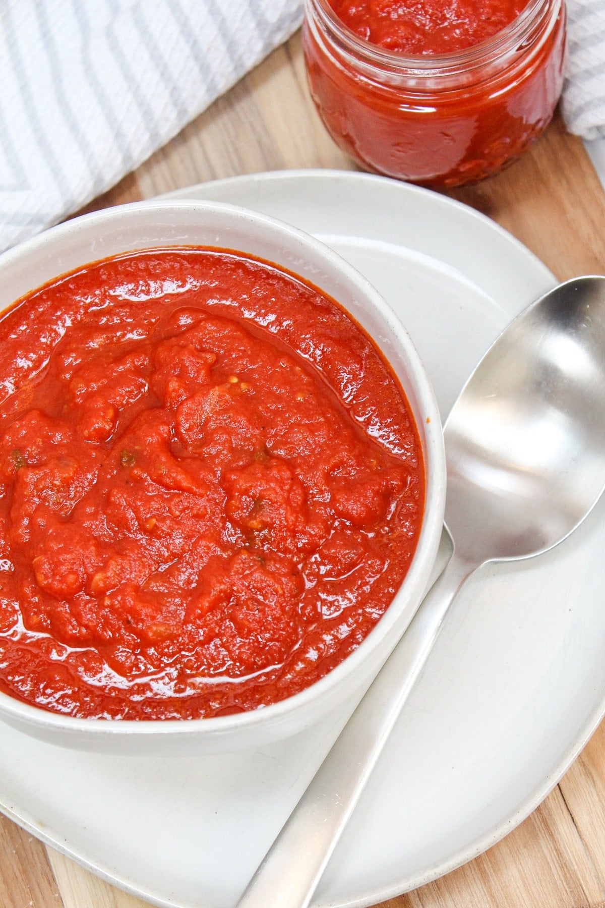 red tomato sauce in a white bowl with a silver spoon.