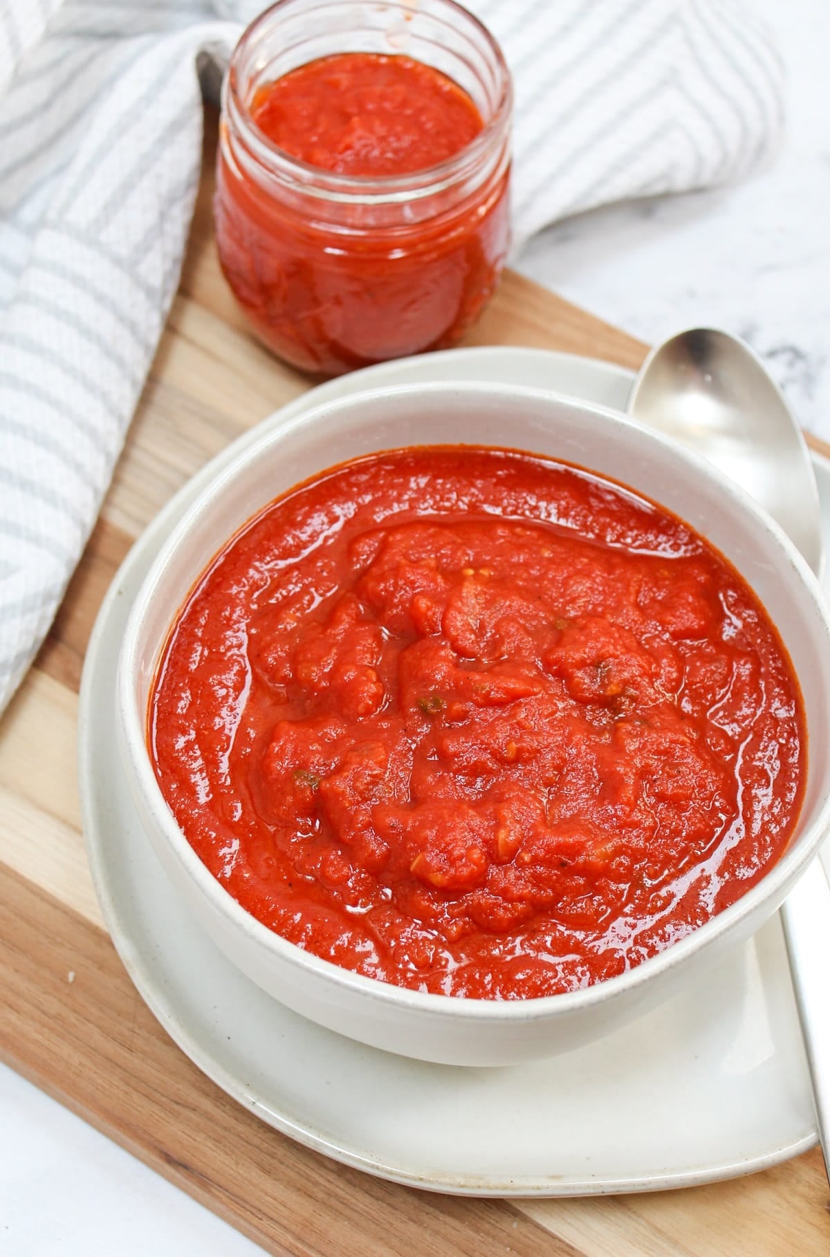 red tomato sauce in a white bowl with a silver spoon.