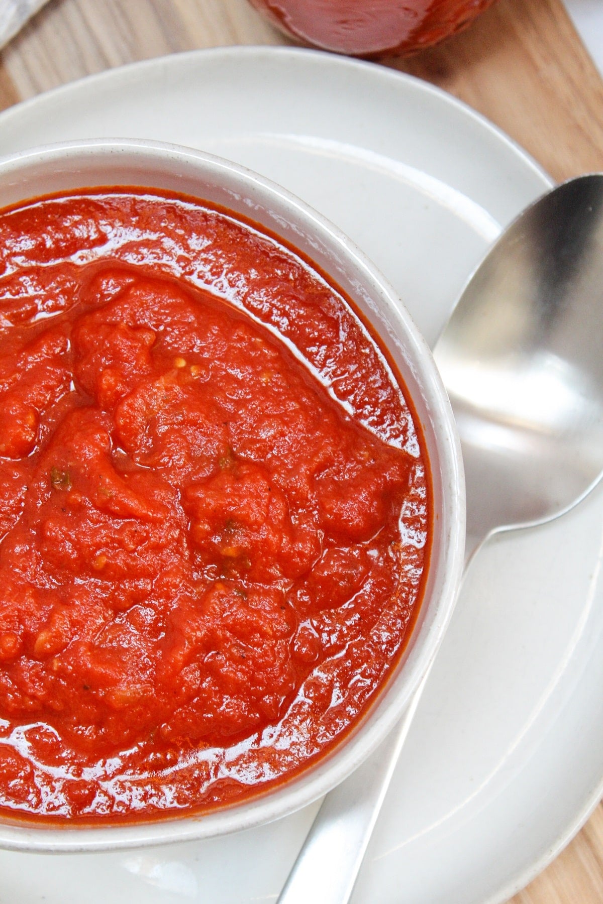 red tomato sauce in a white bowl with a silver spoon.
