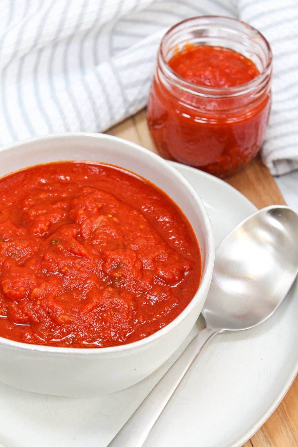 red tomato sauce in a white bowl with a silver spoon.