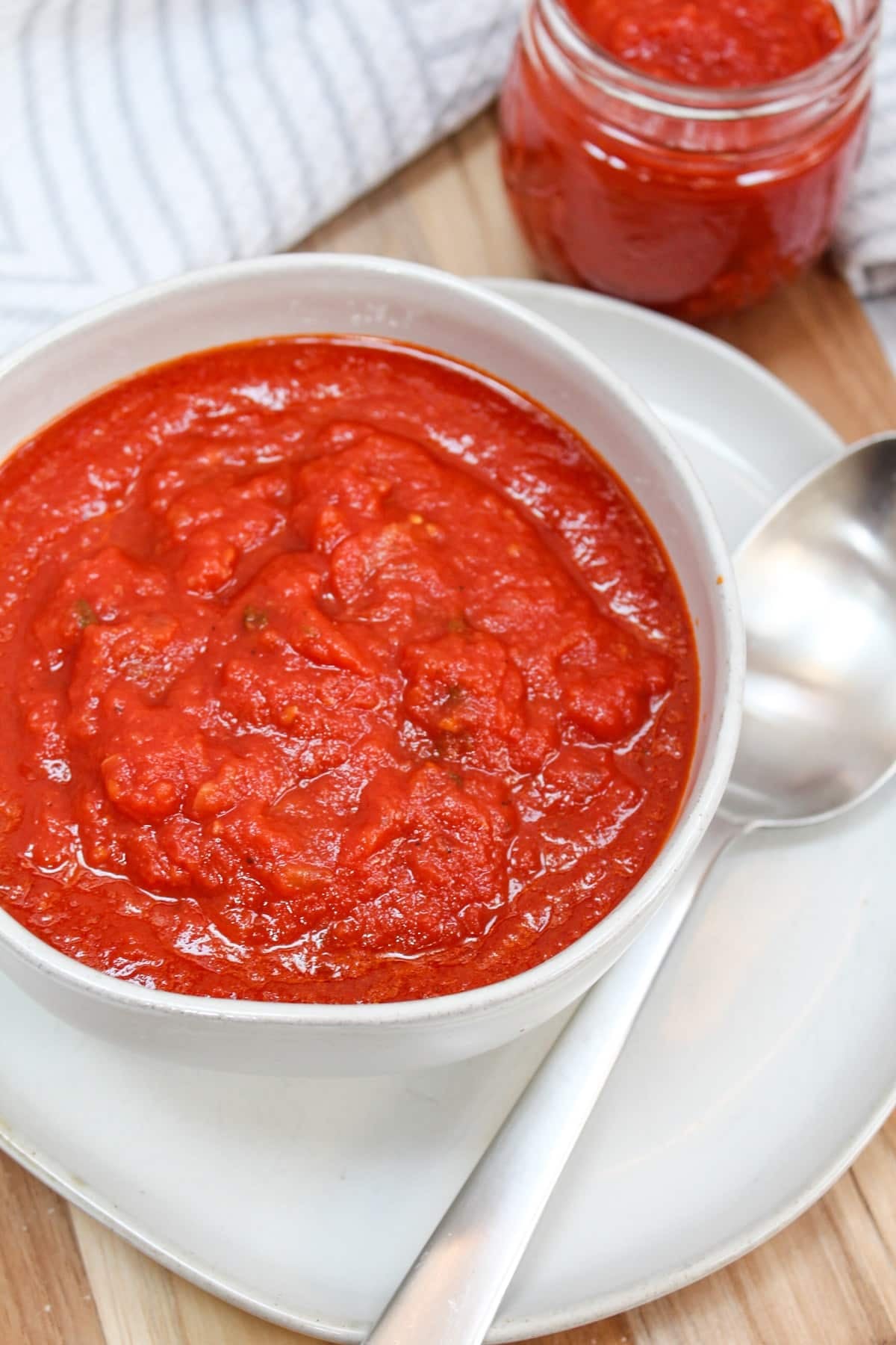 red tomato sauce in a white bowl with a silver spoon.