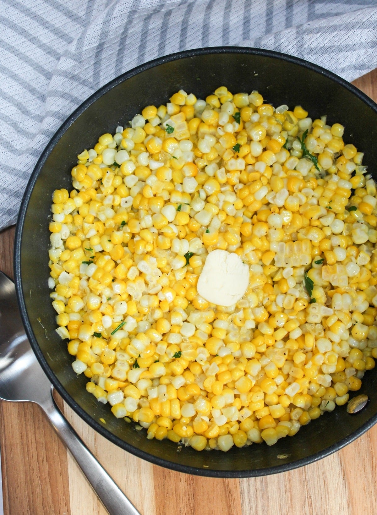 Cooked corn in black skillet with butter on top.