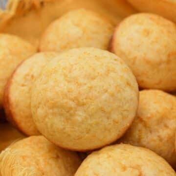 Muffins in a basket with a yellow cloth. Muffins are stacked on each other.
