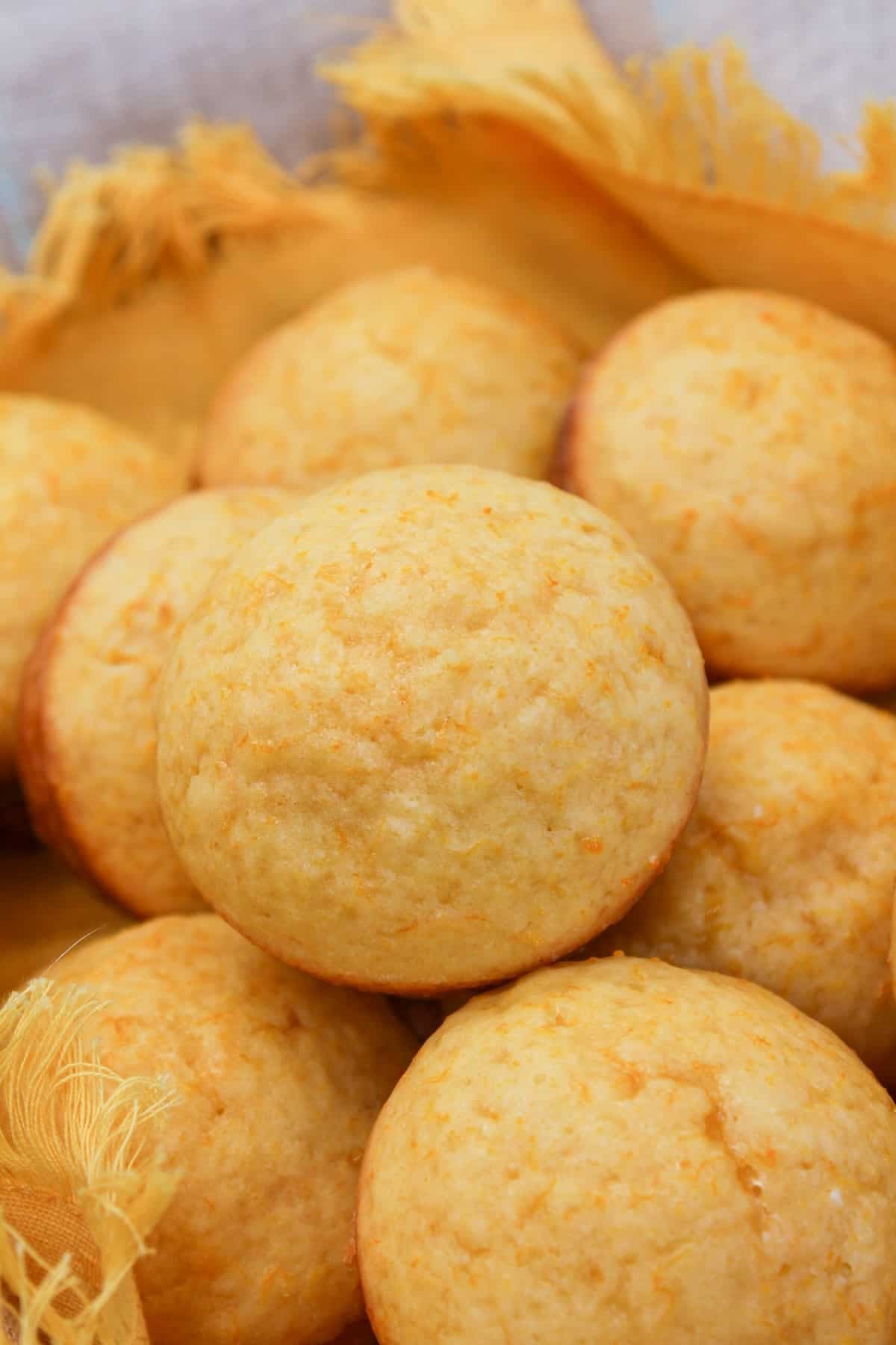 Muffins in a basket with a yellow cloth. Muffins are stacked on each other.