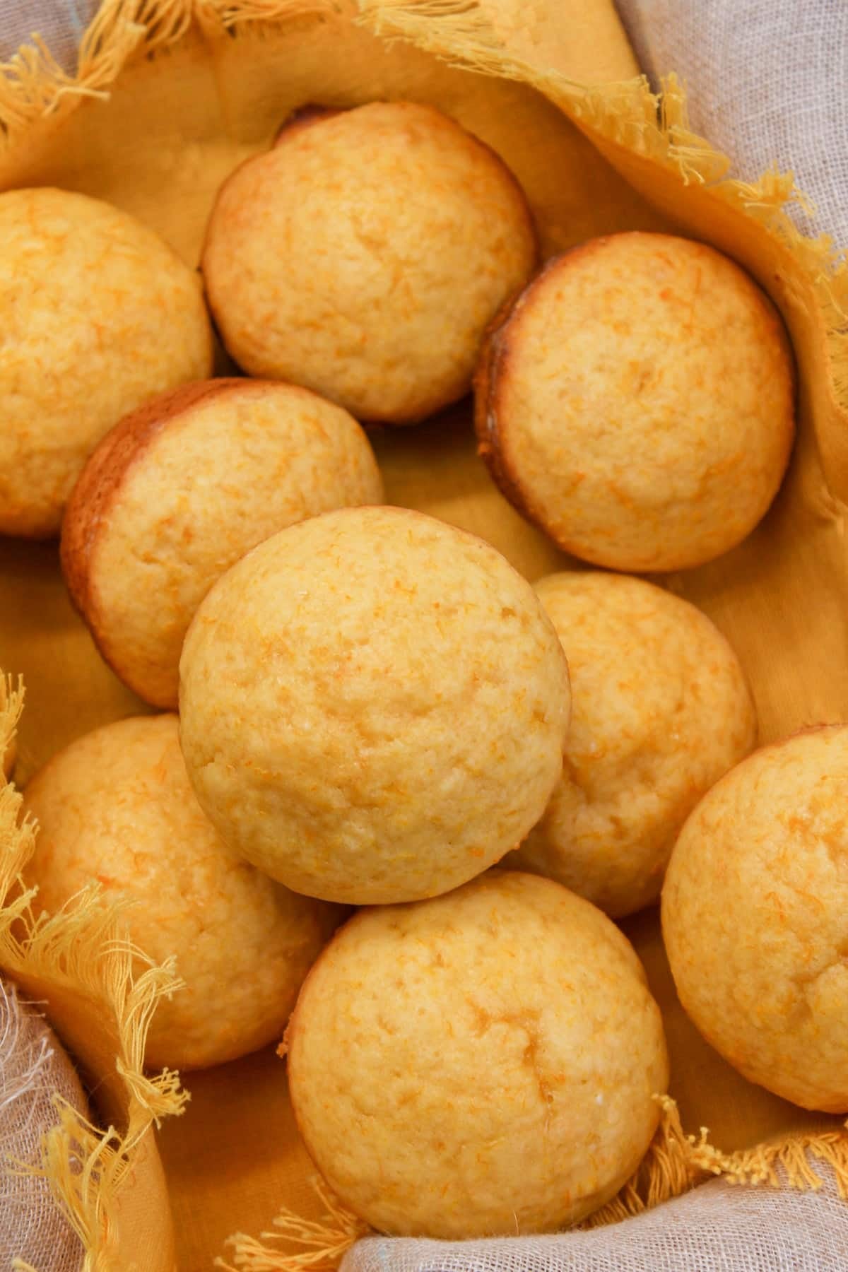 Muffins in a basket with a yellow cloth. Muffins are stacked on each other.