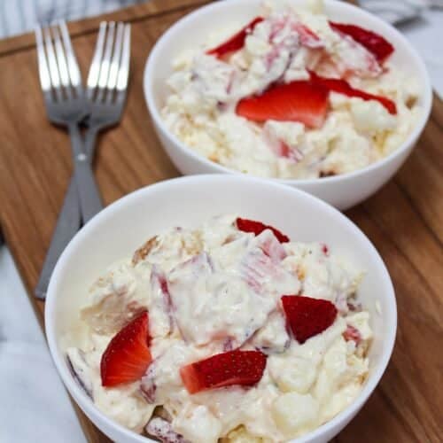dessert conntaining strawberries, pudding, whipped topping, and angel food cake mixed together in a white bowl.
